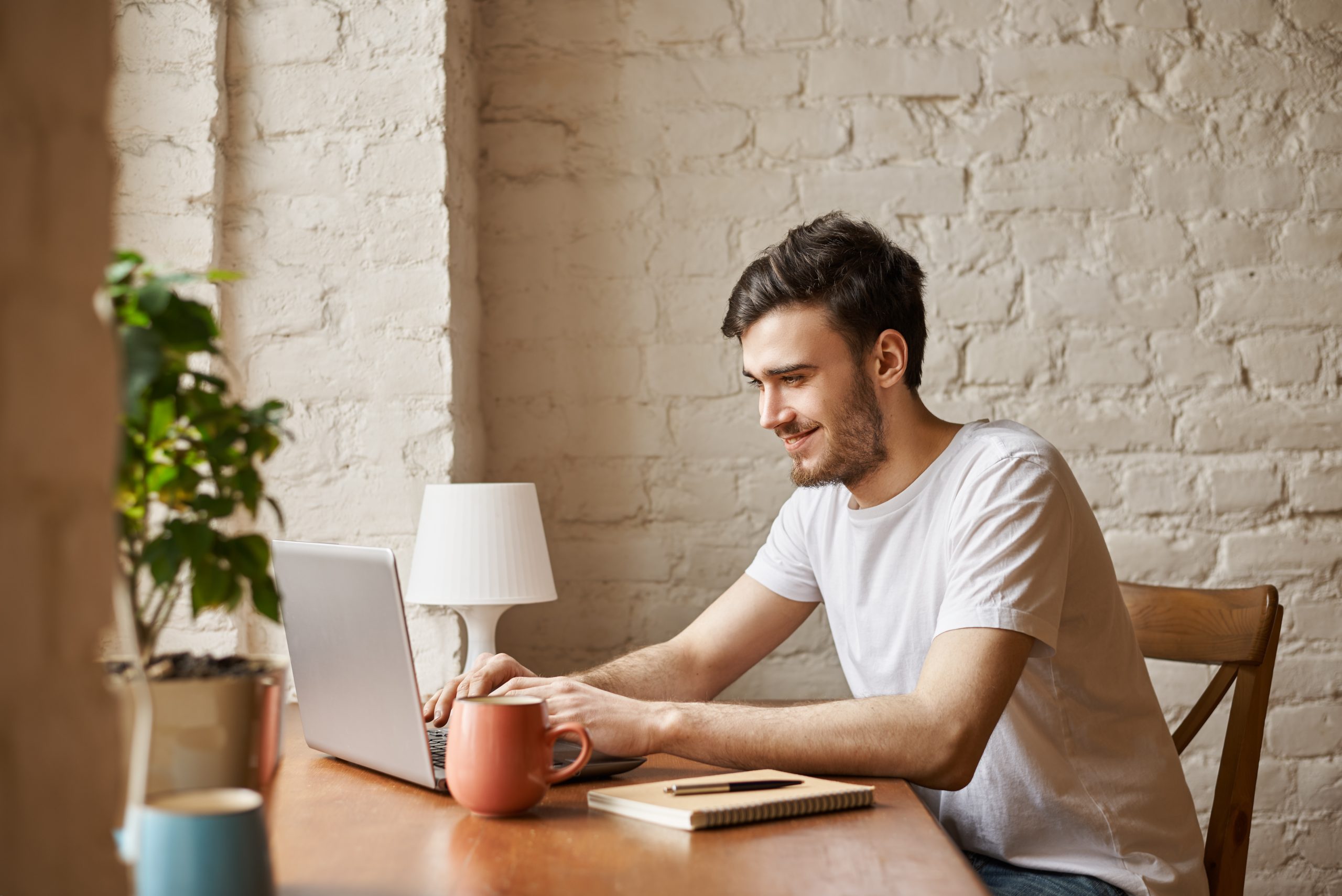 Young man at laptop. The young man is smiling.